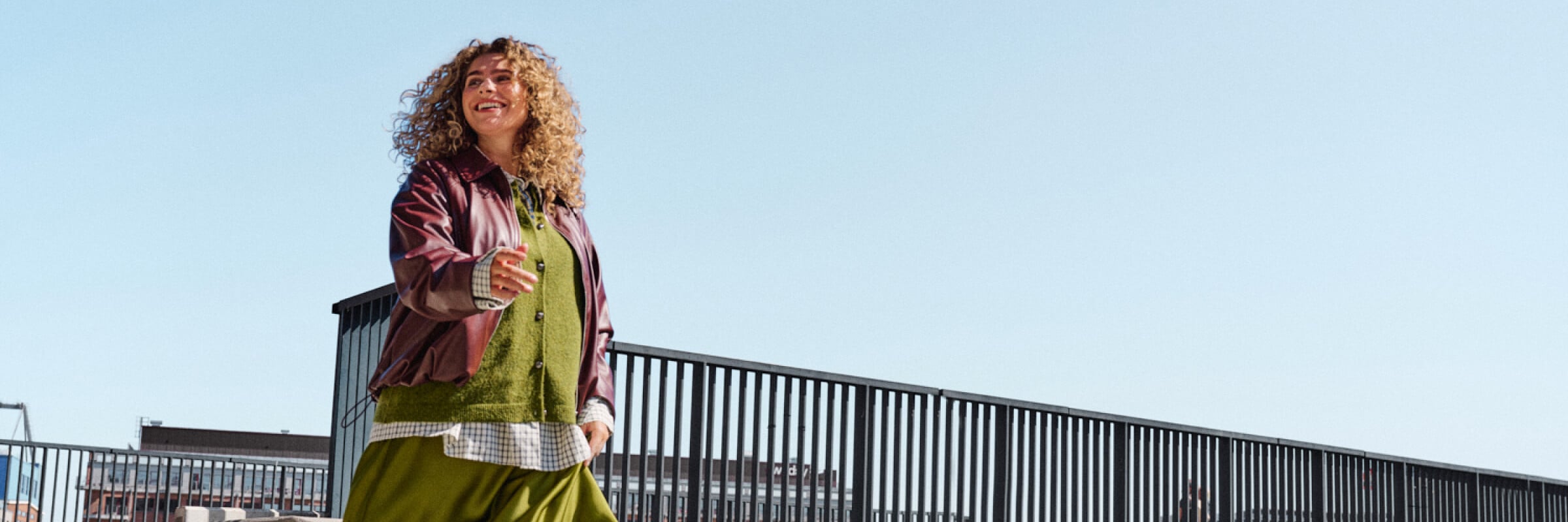Model in einem flie&szlig;enden gr&uuml;nen Satinrock, gr&uuml;nem Pullover und bordeauxroter Jacke, das eine Treppe hinuntergeht