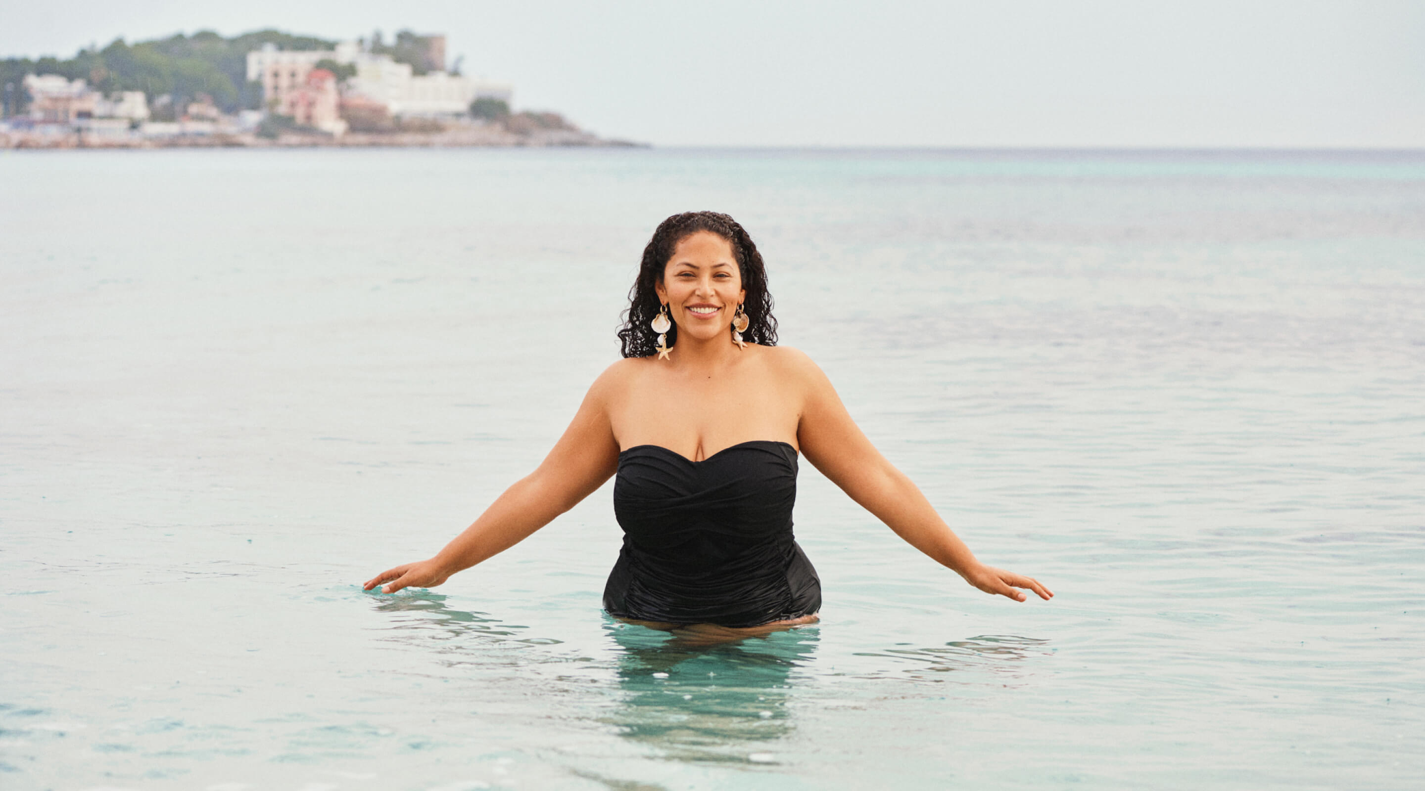 Model in einem weißen Bikini-Top am Hafen mit Schwimmern